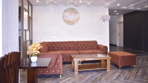 En moderne stue med en brun sofa, et glasbord og en hvid vase med blomster.