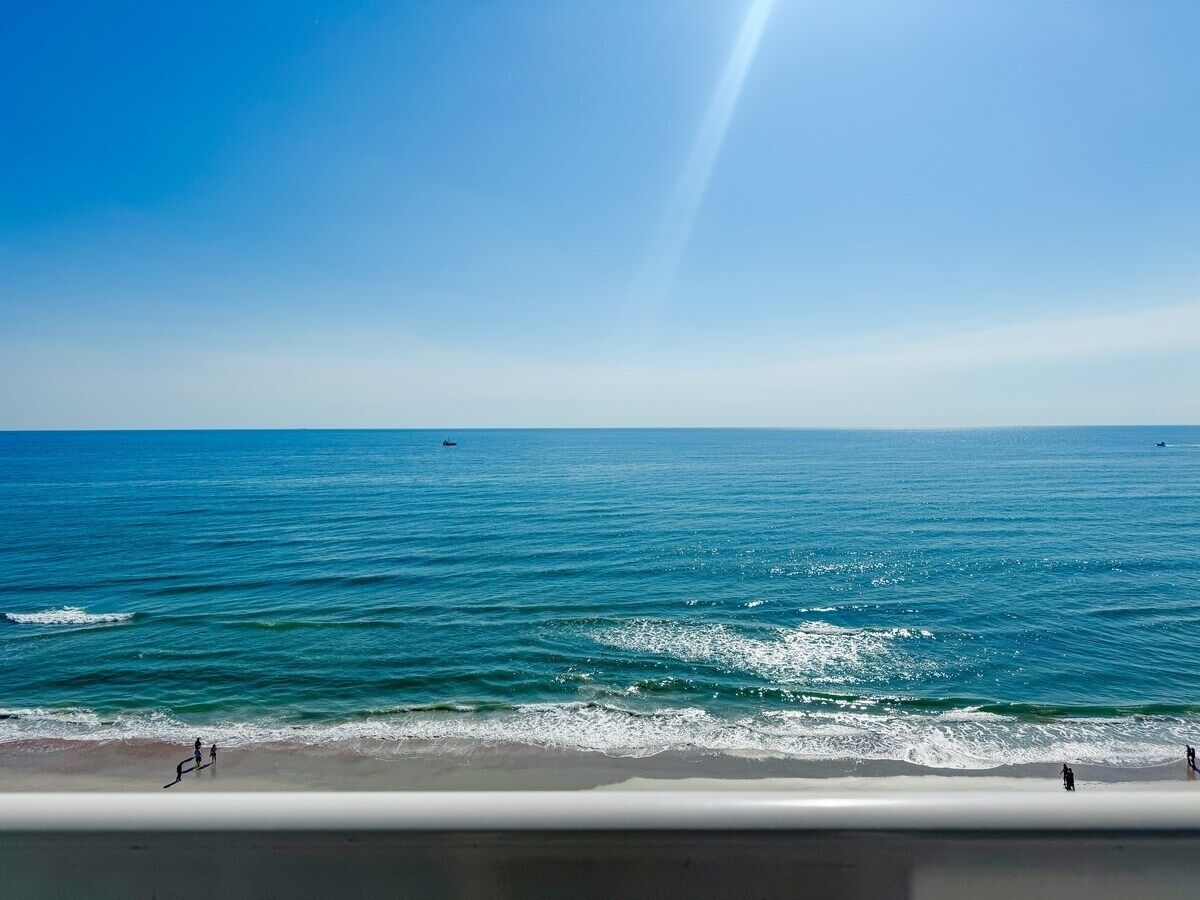 Blick auf einen Strand mit blauem Himmel und ruhiger See.