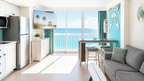 A modern kitchen with a large window, a dining area with a view of the ocean, and a living room with a sofa and a surfboard. - The Atlantic | Direct Oceanfront | 10th Floor (Daytona Beach)