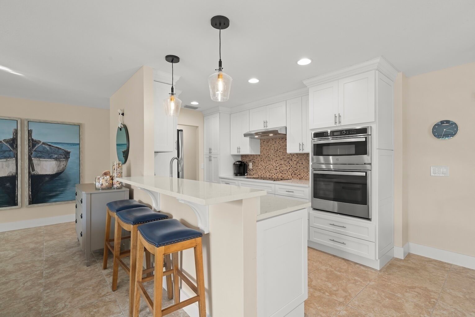 A modern kitchen with white cabinets, stainless steel appliances, and a central island with bar stools.