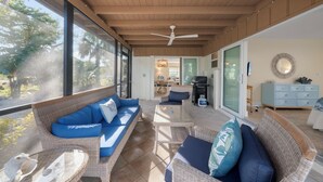 A spacious living area with a ceiling fan, wicker furniture, and a view of the outdoors. - Tahitian Waters: Pet-Friendly Pool Home Just Steps to the Beach! (Sanibel)