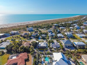 An aerial view of a coastal residential area with houses, a beach, and a clear sky. - Tahitian Waters: Pet-Friendly Pool Home Just Steps to the Beach! (Sanibel)