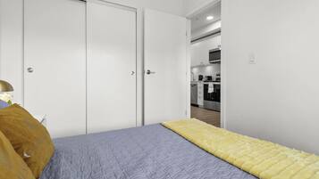 Un dormitorio con una cama, un edredón amarillo y una mesita de noche con una lámpara.
