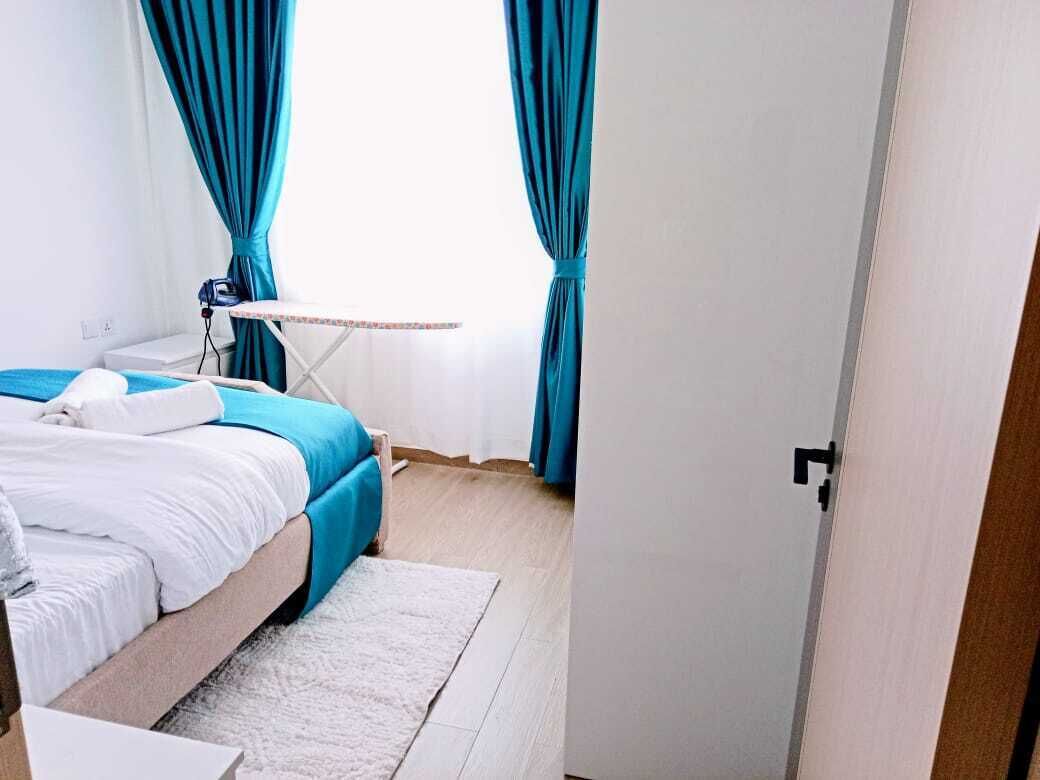 A bedroom with a bed, a small table, and curtains.