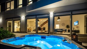 Een modern gebouw met een grote hottub op de voorgrond.