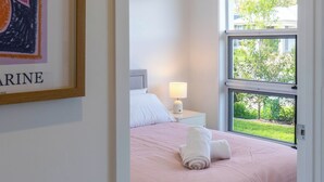 Une chambre à coucher avec un lit, un ventilateur de plafond, une fenêtre et un tableau encadré au mur.