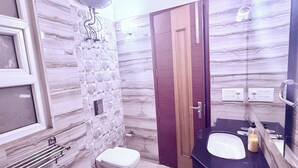 A bathroom with a marble wall, a wooden door, a toilet, a sink, and a towel rack. - STAR INN (Gurugram)