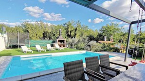 A swimming pool with lounge chairs and a barbecue area in a backyard setting. - Two-storey house with pool in village of Štrika (Umag)