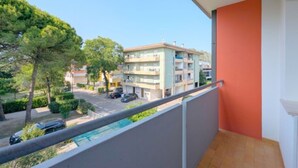 Een balkon met uitzicht op een woongebouw, een parkeerplaats en bomen.