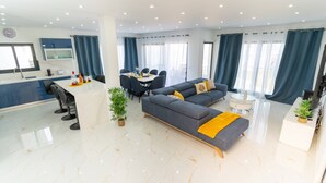 Uma sala de estar moderna com sofá, mesa de jantar e área de cozinha com pia e armários.