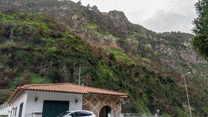 A building with a tiled roof, a garage, and a car parked in front. - Madeira Inn Paradise By Madeira Real (Ribeira Brava)