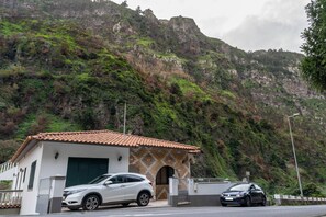 Un bâtiment avec un toit en tuiles, un garage et une voiture garée devant.