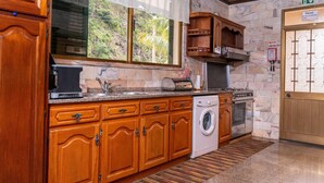 Una cocina con armarios de madera, lavadora, estufa y ventana con vistas a zonas verdes.