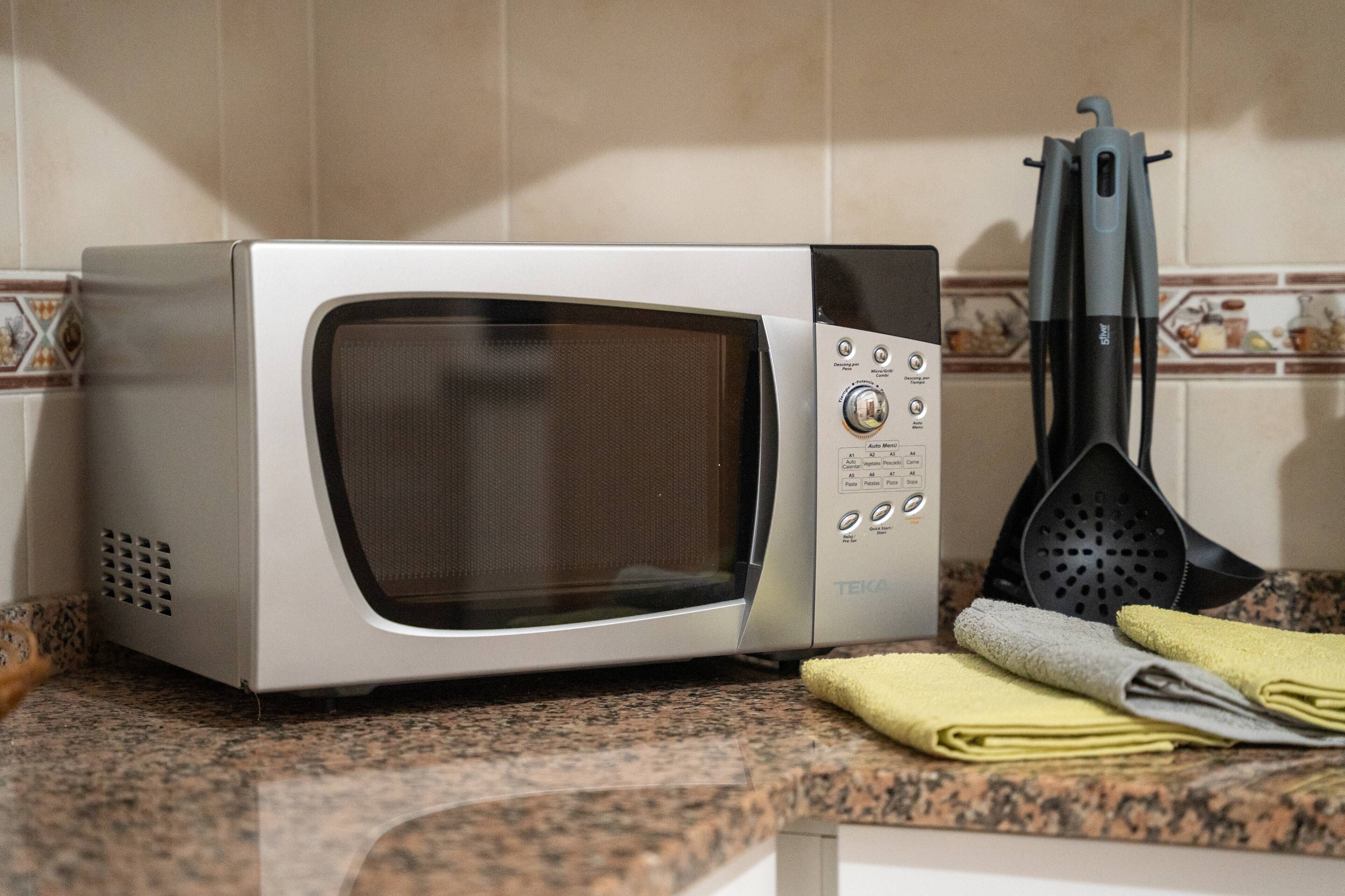 A kitchen with a microwave, a spatula holder, and a towel on the counter.