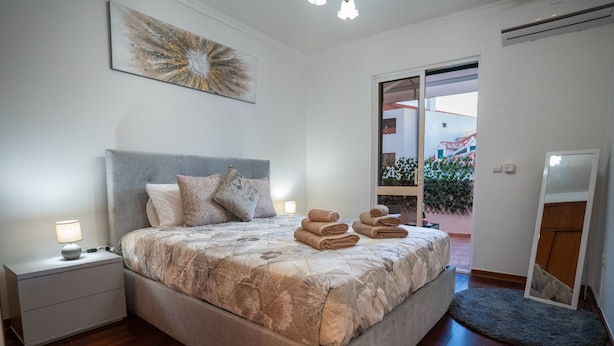 Een slaapkamer met een groot bed, een nachtkastje, een spiegel en uitzicht op buiten.