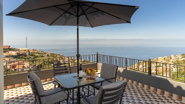 A balcony with a table, chairs, and a large umbrella.