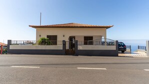 A building with a tiled roof, a gated entrance, and a paved area in front.