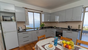 A kitchen with a dining table set for two, featuring a fruit bowl and a carton of milk.