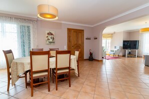 Un comedor con mesa y sillas, una puerta de madera, un televisor y un mueble para televisión.