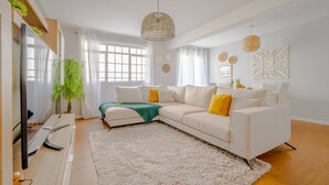 Een moderne woonkamer met een witte bank, een zacht tapijt en een groot raam.