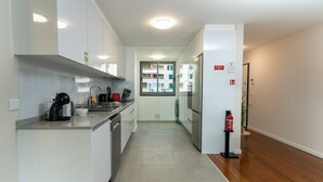 Een moderne keuken met witte kasten, roestvrijstalen apparatuur en een betegelde vloer.