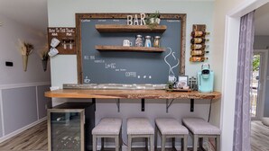 A kitchen bar area with a chalkboard menu, bar stools, a coffee machine, and wine bottles on shelves. - Located in Keenwick Sound with Backyard Oasis: fire pit, bar, & TV; Community Pool & Boat/Kayak launch (Selbyville)