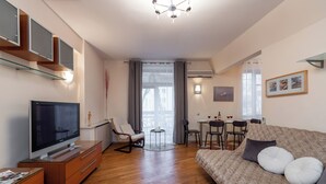 A modern living room with a flat-screen TV, wooden furniture, a sofa with cushions, and a dining area with chairs and a table. - Spacious apartments near Pobedy Square (Minsk)