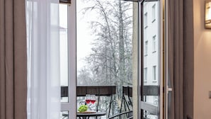 A modern room with a sliding glass door leading to a balcony with outdoor furniture. - Spacious apartments near Pobedy Square (Minsk)