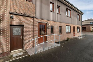 Un bâtiment à deux étages, doté d’une façade en briques et d’un toit en métal.