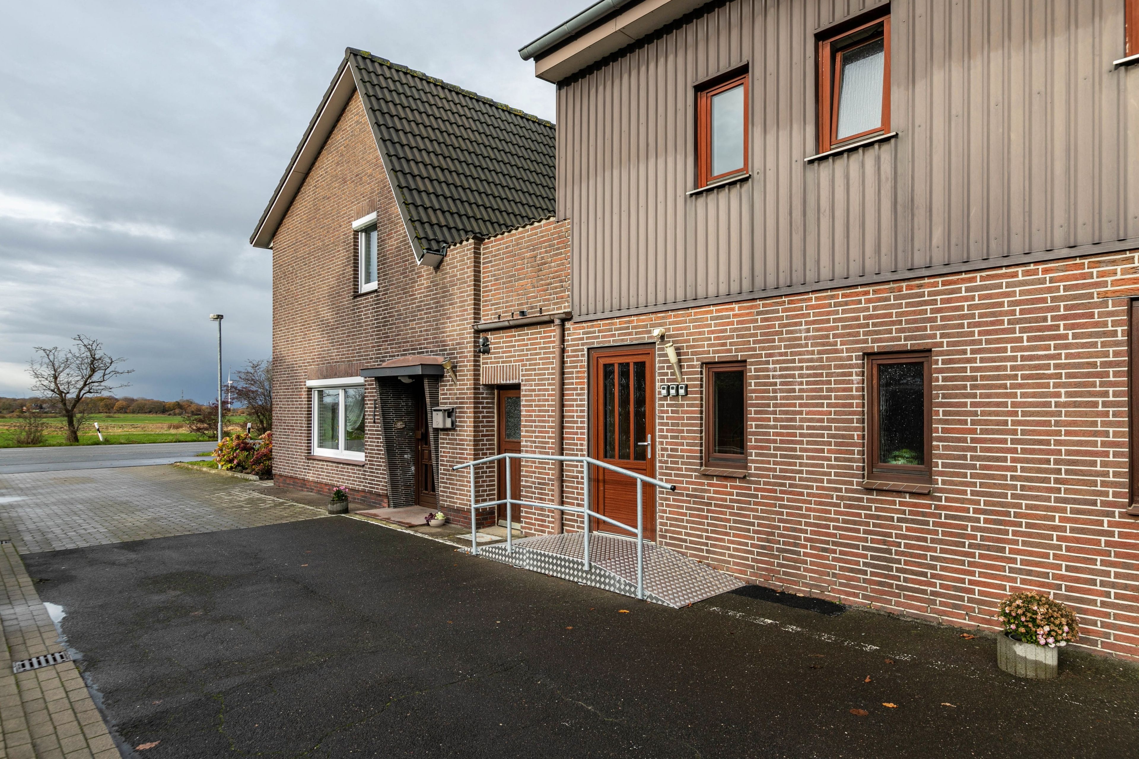 A two-story building with a brick facade, a metal roof, and a gated entrance.