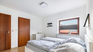 Ein Schlafzimmer mit Doppelbett, einem Schminktisch, einem Fenster mit Aussicht und einer Tür.