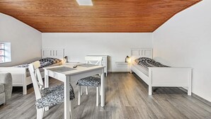 A modern, minimalist room with a wooden ceiling, white furniture, and a grey floor. - Apartment 'Small Holiday  3 Monteurs' with Shared Garden and Wi-Fi (Weddingstedt)