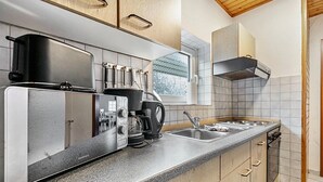 A modern kitchen with a built-in oven, coffee maker, and kettle. - Apartment 'Small Holiday  3 Monteurs' with Shared Garden and Wi-Fi (Weddingstedt)