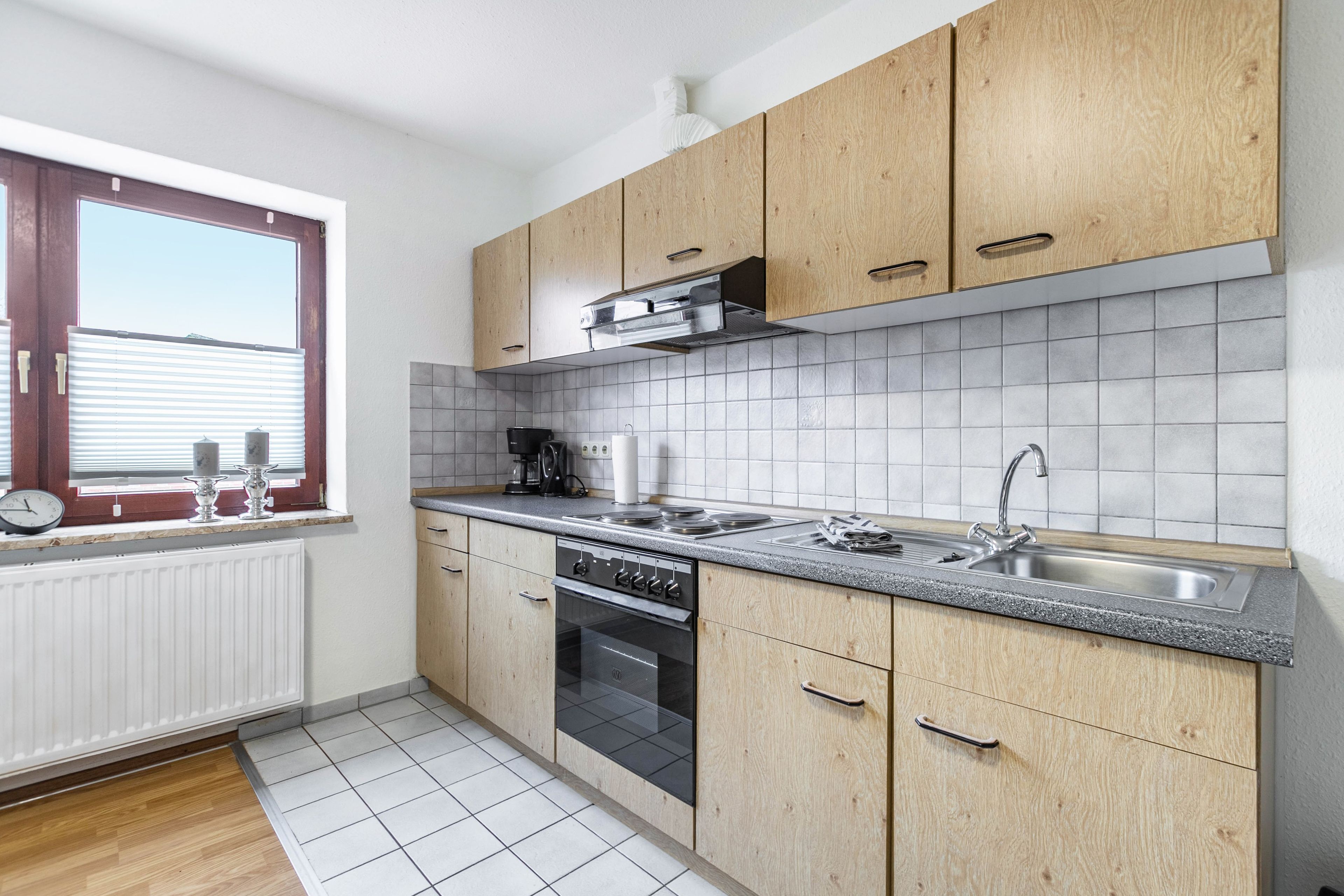 Une cuisine moderne avec des meubles en bois, un évier en acier inoxydable et un four encastré.
