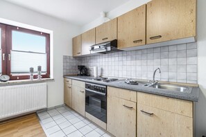 Une cuisine moderne avec des meubles en bois, un évier en acier inoxydable et un four encastré.