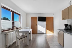 Een moderne keuken met een eethoek, houten kastjes, een koffiezetapparaat en uitzicht door een raam.