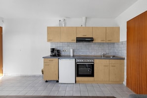 Une cuisine compacte avec des meubles de rangement en bois, un lave-vaisselle, une cuisinière et une machine à café.