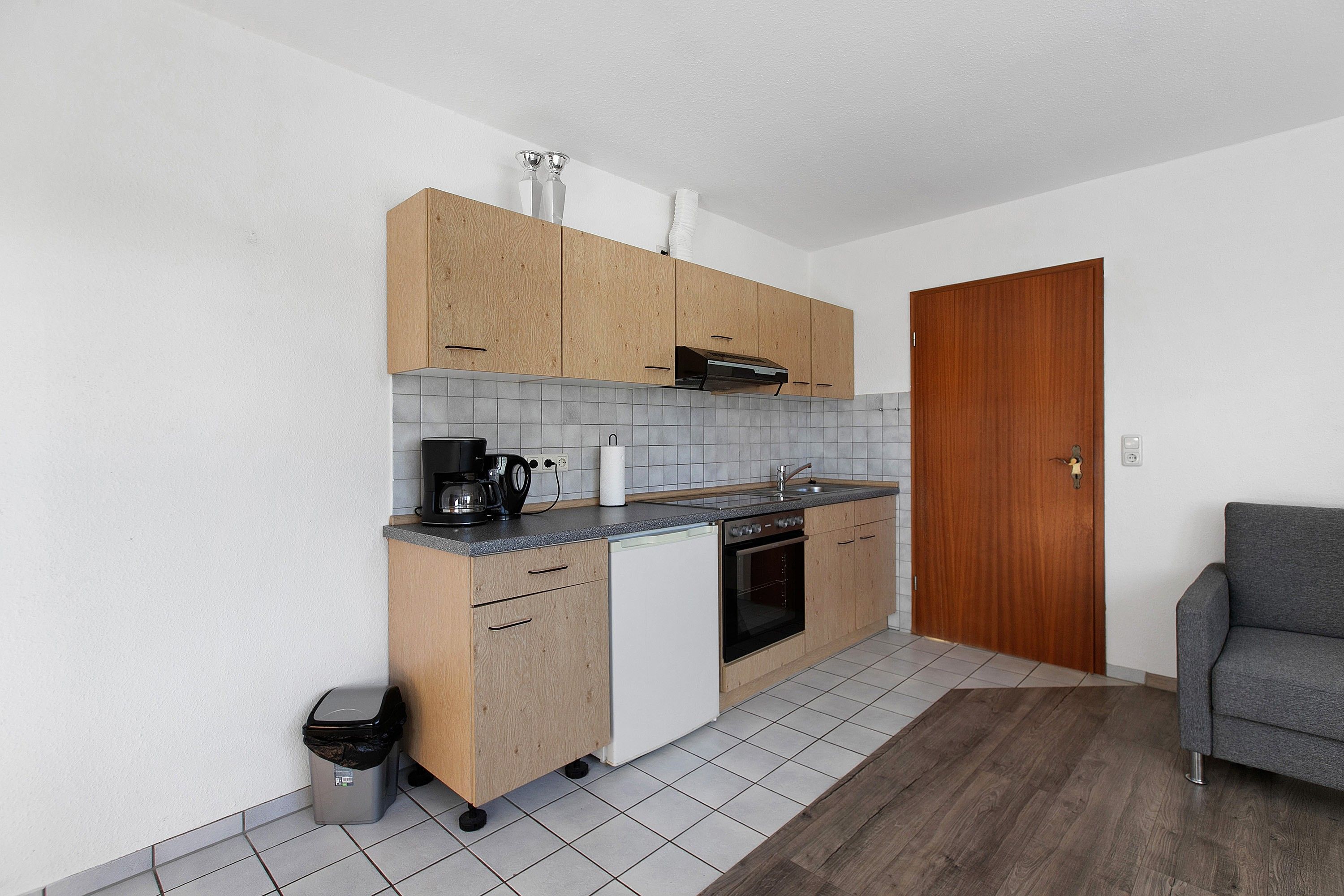 Une cuisine compacte avec des meubles de rangement en bois, un four encastré et un petit plan de travail.
