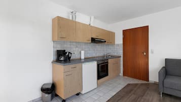 Une cuisine compacte avec des meubles de rangement en bois, un four encastré et un petit plan de travail.