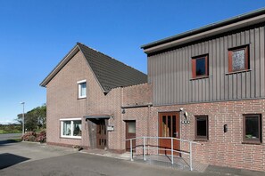 Een gebouw met twee verdiepingen, een gevel van baksteen en een grijs bovenstuk.