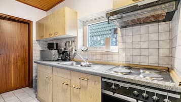 Een keuken met houten kastjes, een inbouwoven en een raam met uitzicht.