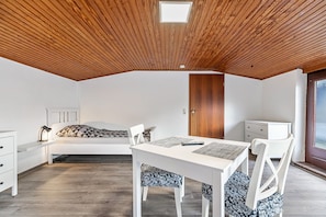 Een kamer met een schuine kap, een bed, een bureau en een stoel.