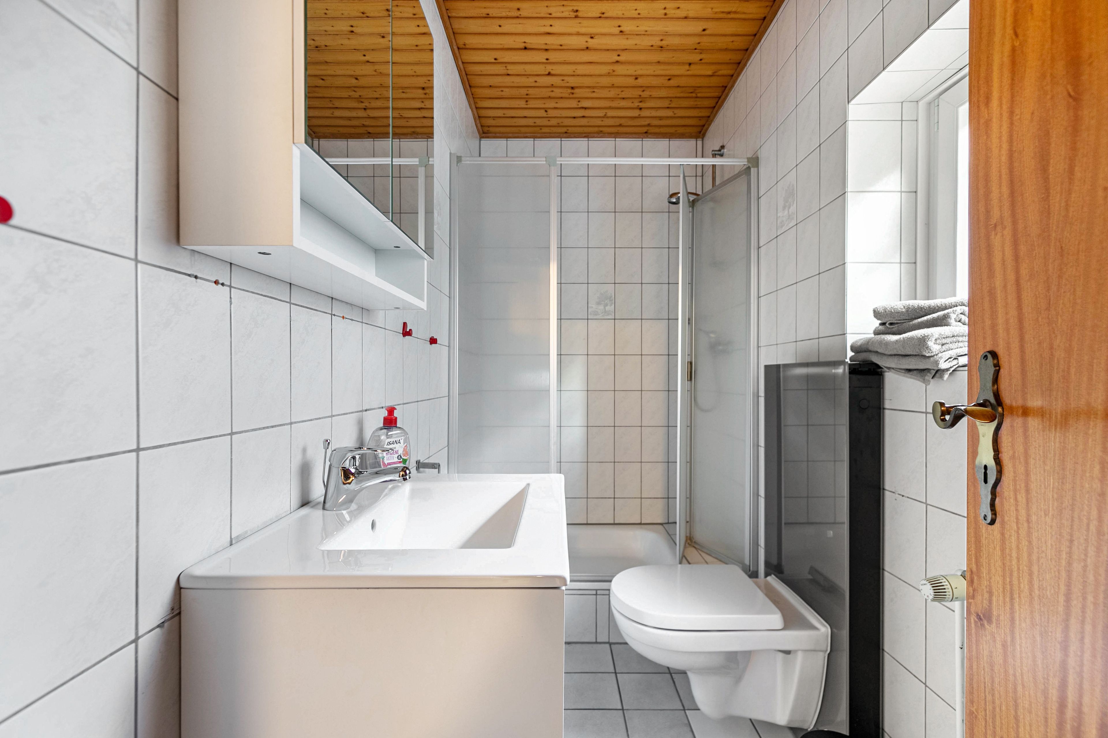 A modern bathroom with a white sink, a toilet, and a shower area.