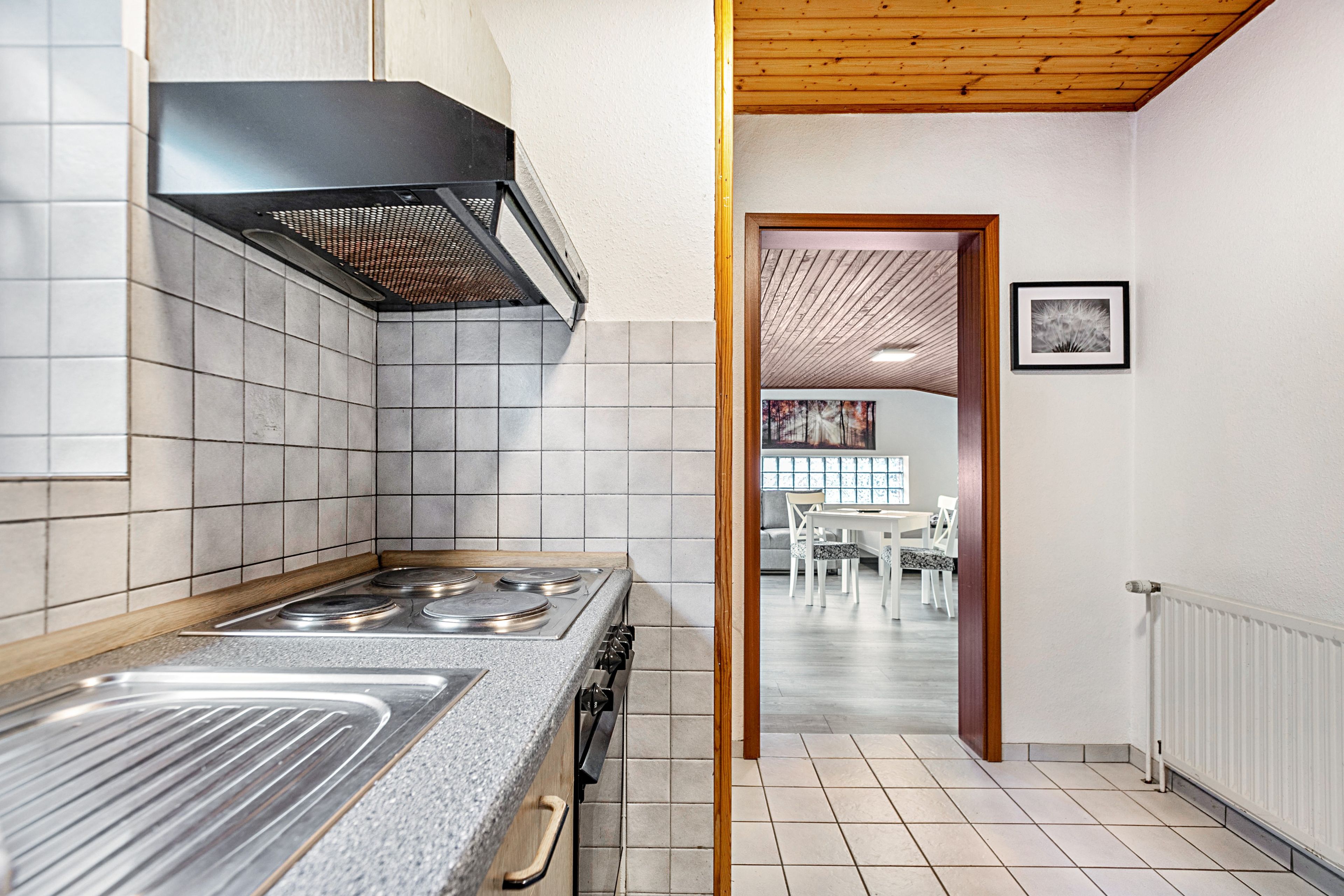 A modern kitchen with a gas stove, a range hood, and a view into a dining area with a table and chairs.