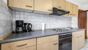 A kitchen with wooden cabinets, a gas stove, a coffee maker, and a sink. - Apartment "Practical Mechanic Room 5" with Shared Garden and Wi-Fi (Weddingstedt)