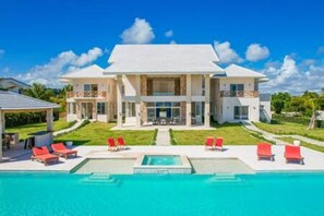 A large, modern house with a swimming pool and red lounge chairs. - Insane Ocean View Cap Cana Villa - Pool Chef Staff (Punta Cana)