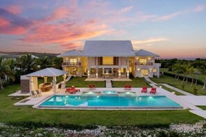 A large, modern house with a swimming pool, multiple balconies, and a well-maintained lawn. - Insane Ocean View Cap Cana Villa - Pool Chef Staff (Punta Cana)