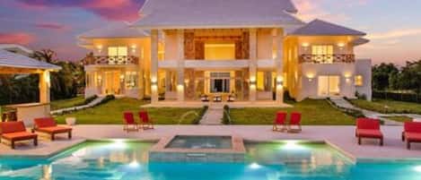 Una casa grande de dos pisos con una piscina al frente.