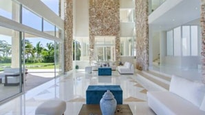 A spacious, modern living area with a large window, a blue accent wall, and a decorative vase on a table. - Insane Ocean View Cap Cana Villa - Pool Chef Staff (Punta Cana)
