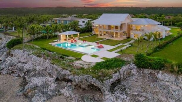 A large house with a swimming pool, surrounded by greenery and a rocky landscape. - Insane Ocean View Cap Cana Villa - Pool Chef Staff (Punta Cana)
